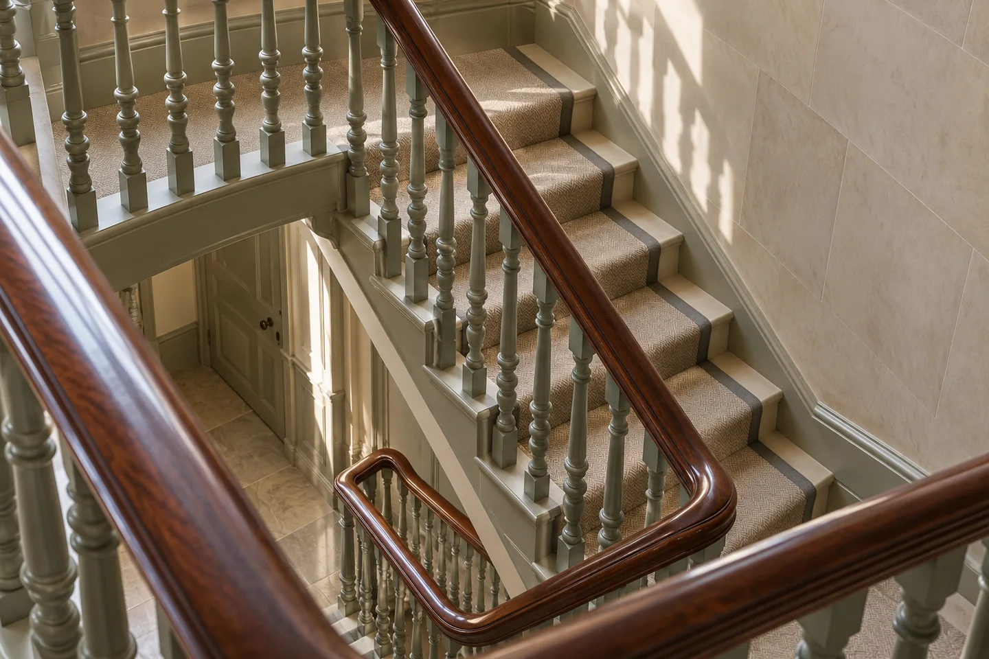 Period townhouse staircase with painted balusters, a mahogany handrail and soft light across the landing